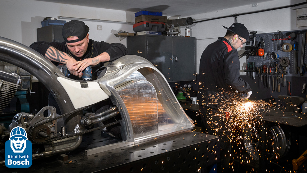 #builtwithbosch - Making of a custom bike. Two men are working in a workshop, one is welding, the other is screwing.