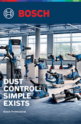 An arrangement of blue Bosch Professional tools on a concrete floor in a bright room. Tools are spread across shelves and the floor, including a vacuum cleaner and various machines. Bright windows provide daylight and a modern atmosphere.