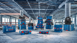 Various blue Bosch Professional toolboxes are standing on a concrete floor in a construction environment.