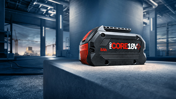 Black Bosch Professional 18V battery pack on a gray concrete block.