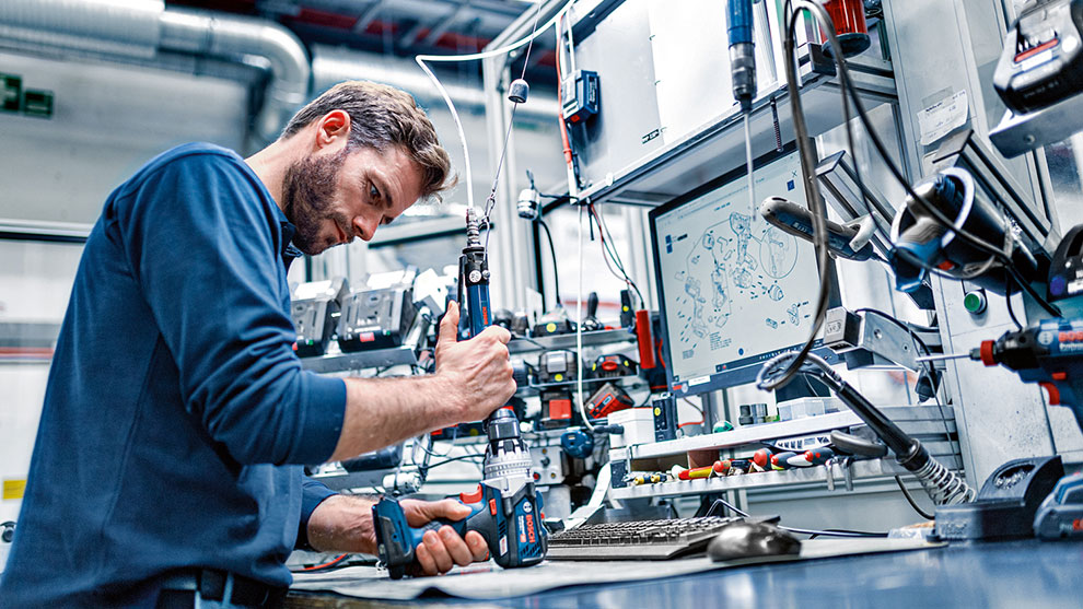A man is working with a Bosch Professional cordless screwdriver at the table.