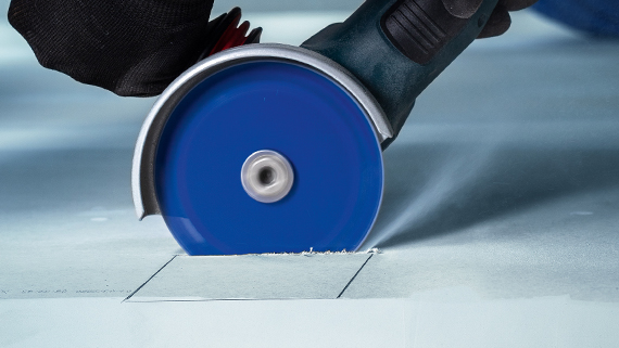 A blue Bosch Professional angle grinder is cutting into a surface.