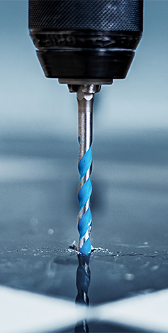 A blue drill with a spiral drill bit penetrates metal.