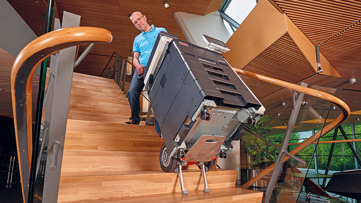 A man is carrying a black Bosch tool case down the stairs.