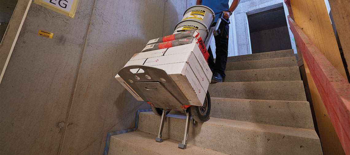 A worker is pushing a cart with materials up the stairs.