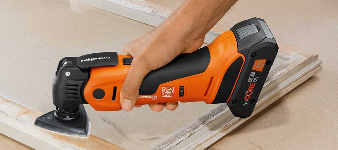 An orange Bosch Professional battery multitool is cutting wooden panels.