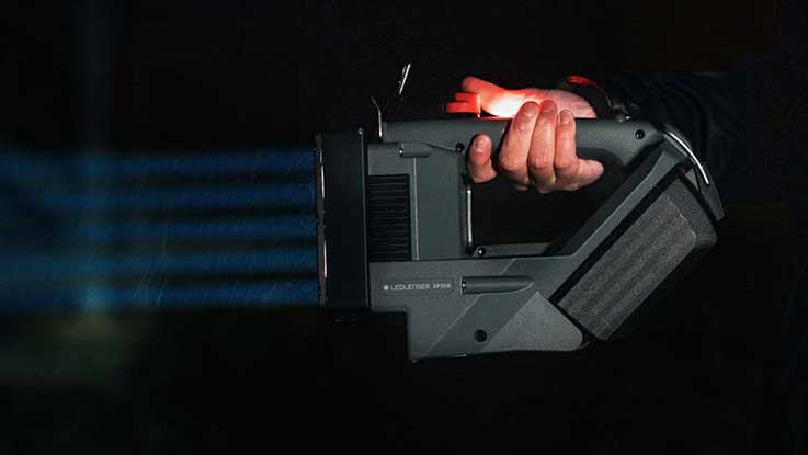 A hand holds a black Bosch Professional projector.