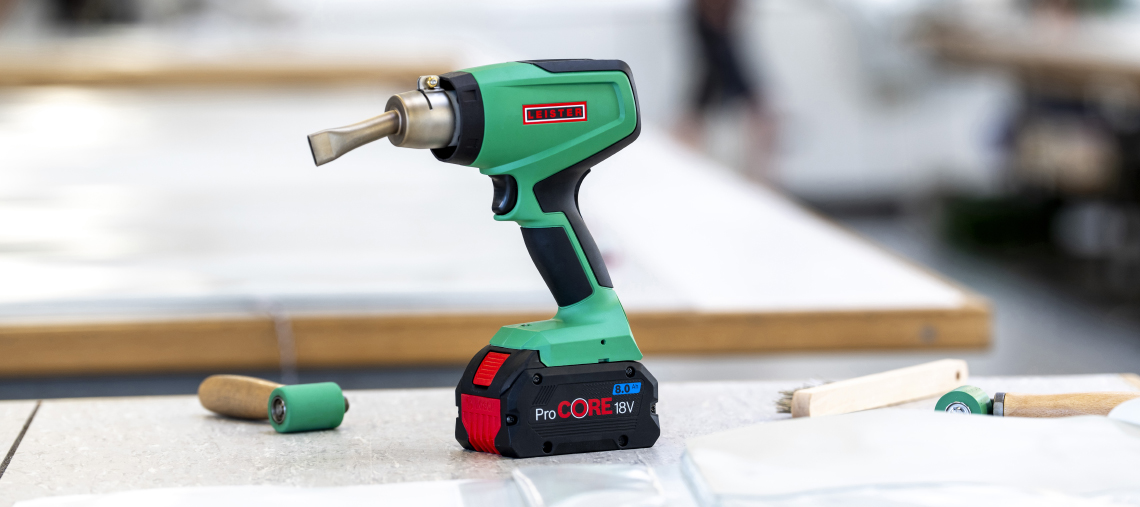 A green Bosch Professional heat gun is lying on a white background.