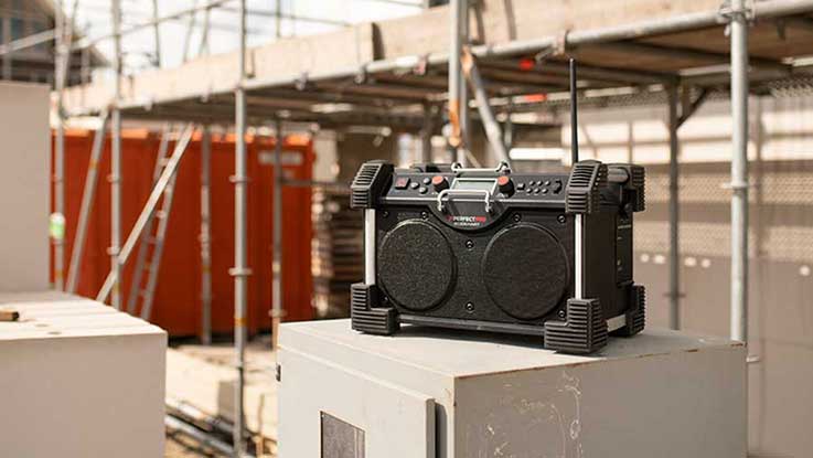 A black Bosch Professional radio is standing on a box at the construction site.