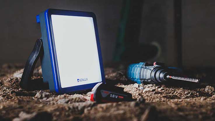 A blue spotlight is on the ground next to a battery-powered screwdriver.