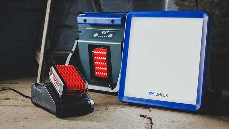 A red SONLUX charger stands next to a white LED spotlight.
