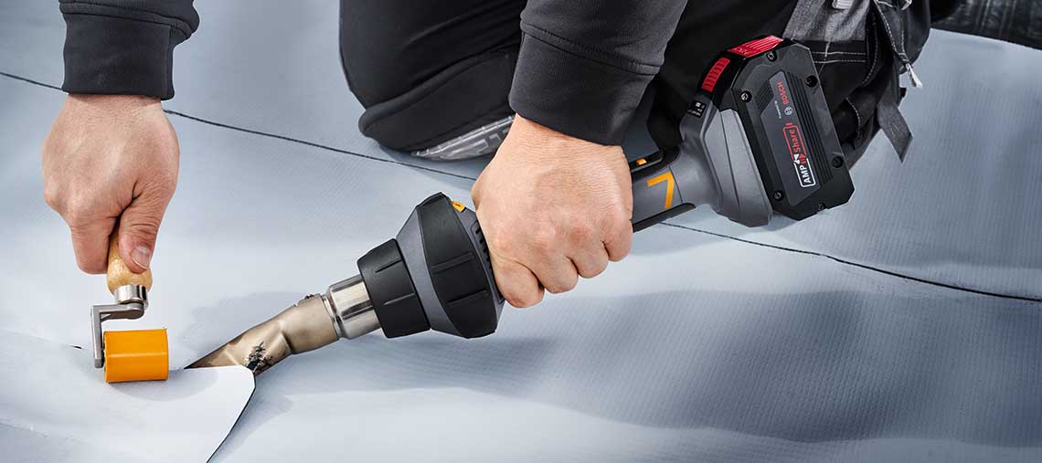 A Bosch Professional heat gun is used on a gray background.