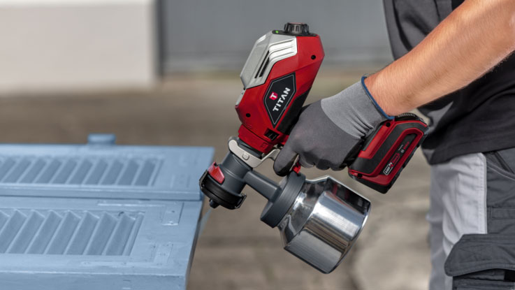 A red TITAN spray device is being used on a blue surface.