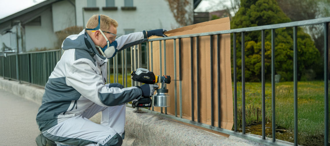 A man in work clothes is spraying with a Bosch Professional tool.