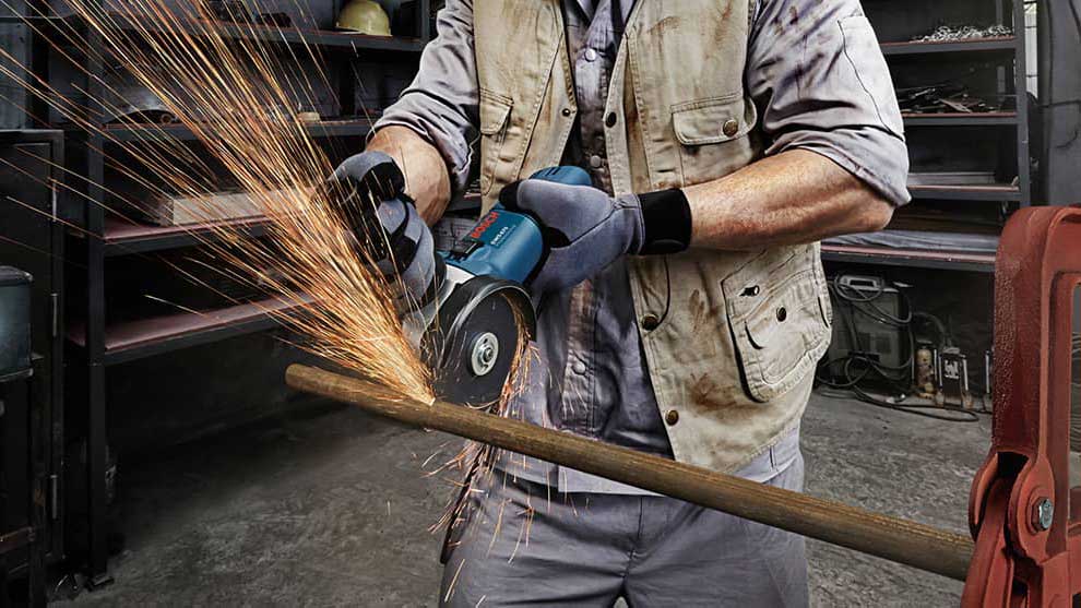 A craftsman is cutting a piece of wood with a Bosch tool.