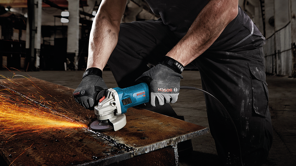 A craftsman uses a blue Bosch Professional angle grinder on metal.