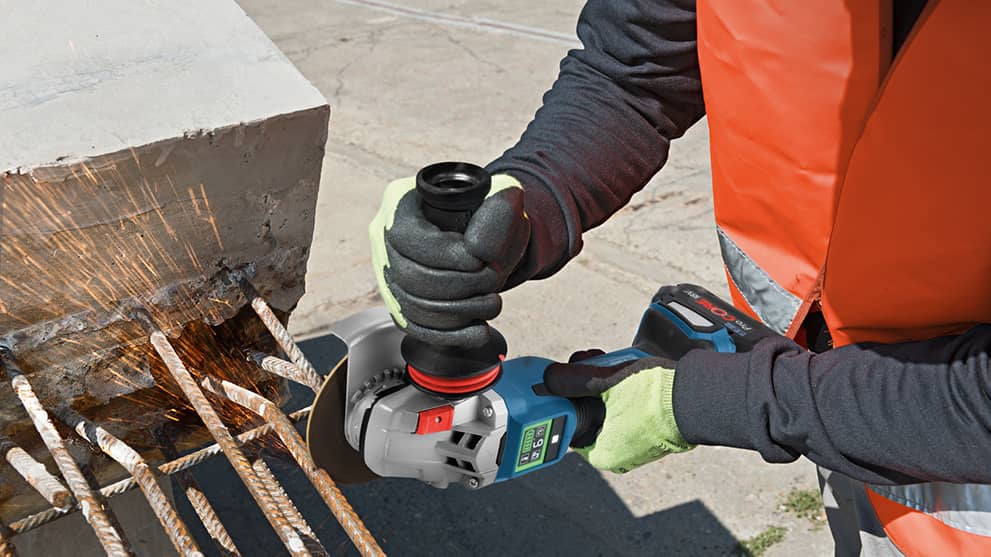 A Bosch Professional angle grinder cuts rebar, sparks fly.