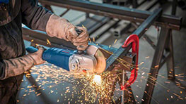 A worker is using a Bosch Professional angle grinder, sparks are flying.