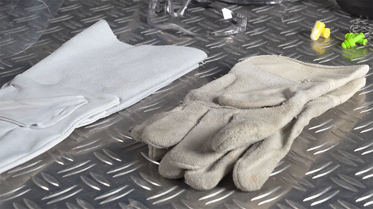 Two work gloves on a metallic surface.
