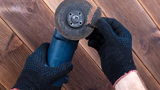 A person is changing a grinding disc on a blue Bosch tool.