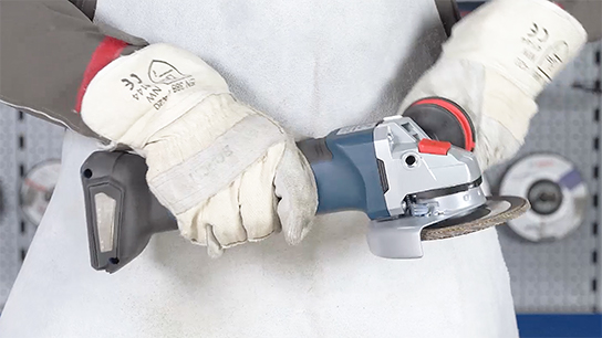 A person is holding a blue Bosch Professional angle grinder with both hands.