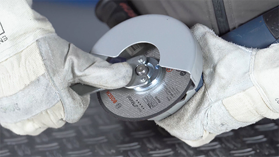 Hands in white gloves hold a Bosch cutting disc.