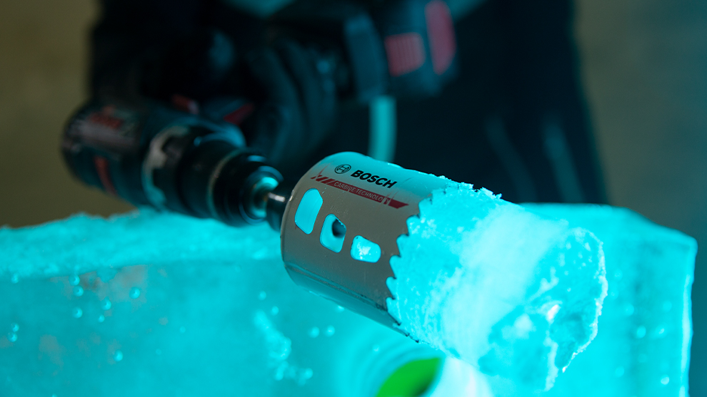 Bosch Professional drill breaks through ice with blue lighting.