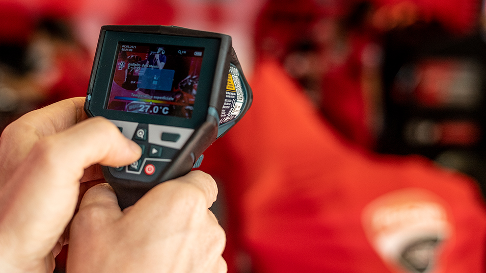 A person is holding a digital thermometer with a display in their hand.