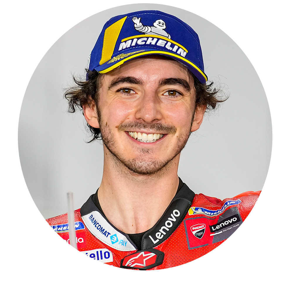 A smiling man in a motorcycle jacket and blue hat poses friendly.