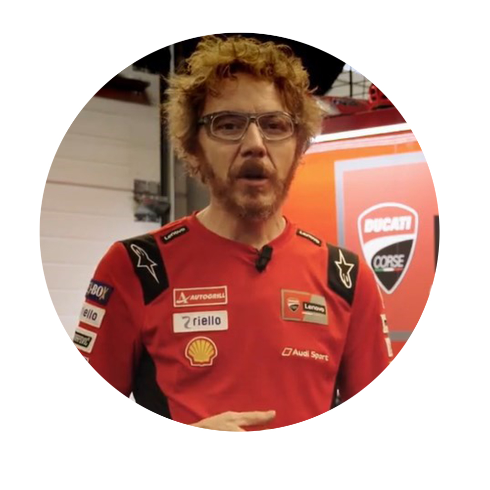 Man with curly hair in red Ducati shirt speaks against a background.