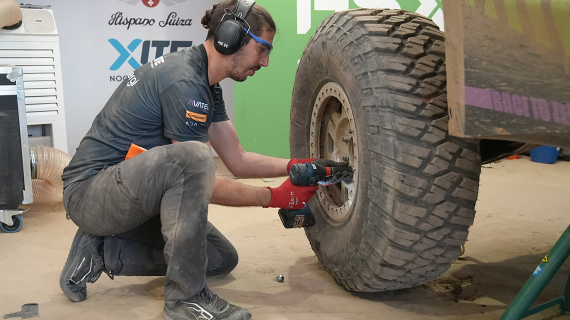 A man is changing a tire with a Bosch tool in a workshop.