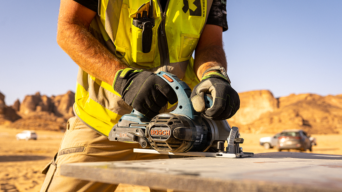 A worker is using a Bosch Professional circular saw in the desert.