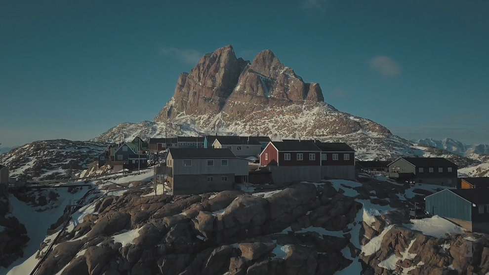 Disappearing ice caps: The Arctic X Prix takes place on land previously occupied by the Russell Glacier in Greenland. Colorful houses at the foot of a snow-covered mountain under a blue sky.