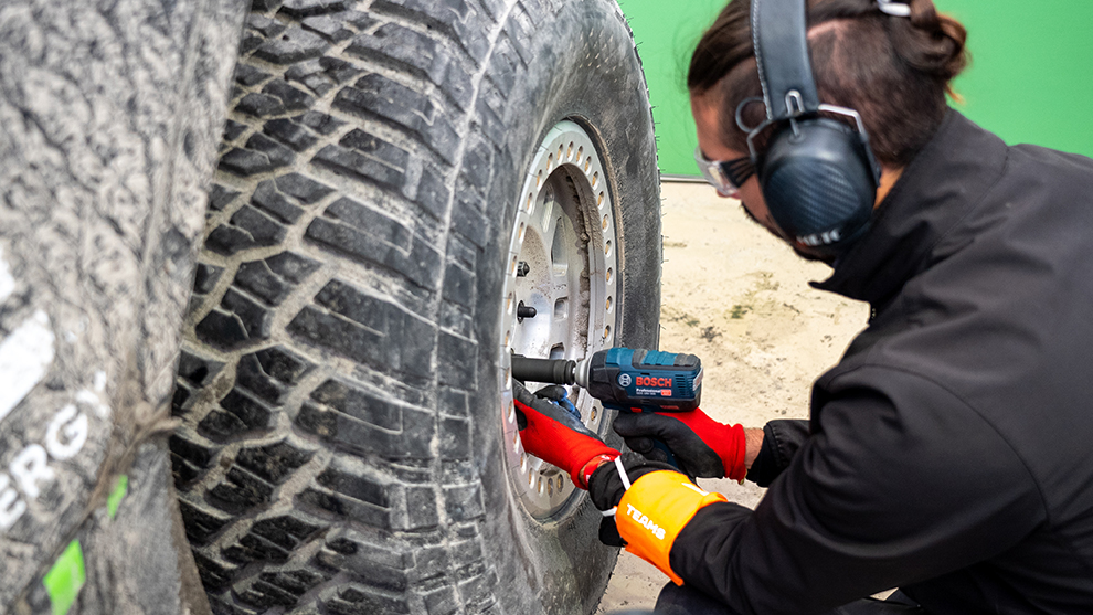 No time to lose: Extreme E mechanics rely on the BITURBO GSD 18V-LI HT Professional impact wrench to change big tyres quickly. A man with protective headphones is using a Bosch screwdriver on the tire.