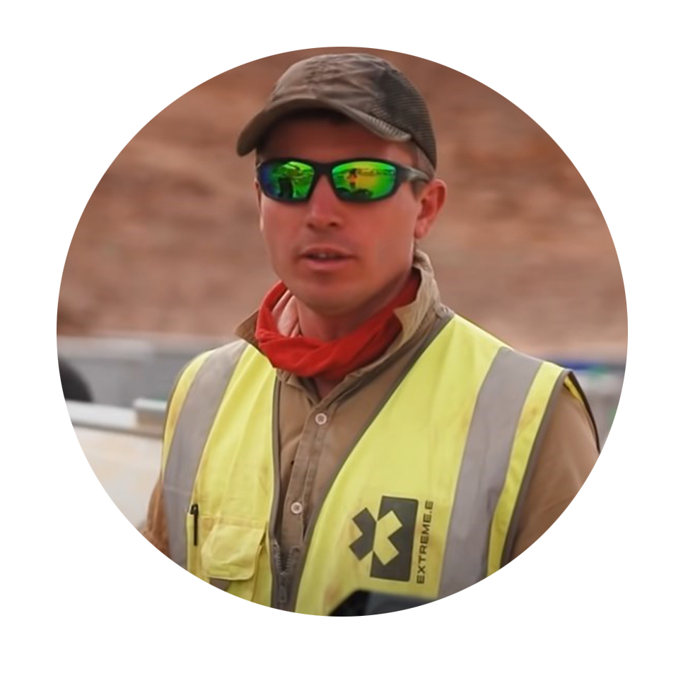 Dougie Dale, Global Production Team of Extreme E Man in yellow safety vest and sunglasses speaks in front of a construction site.