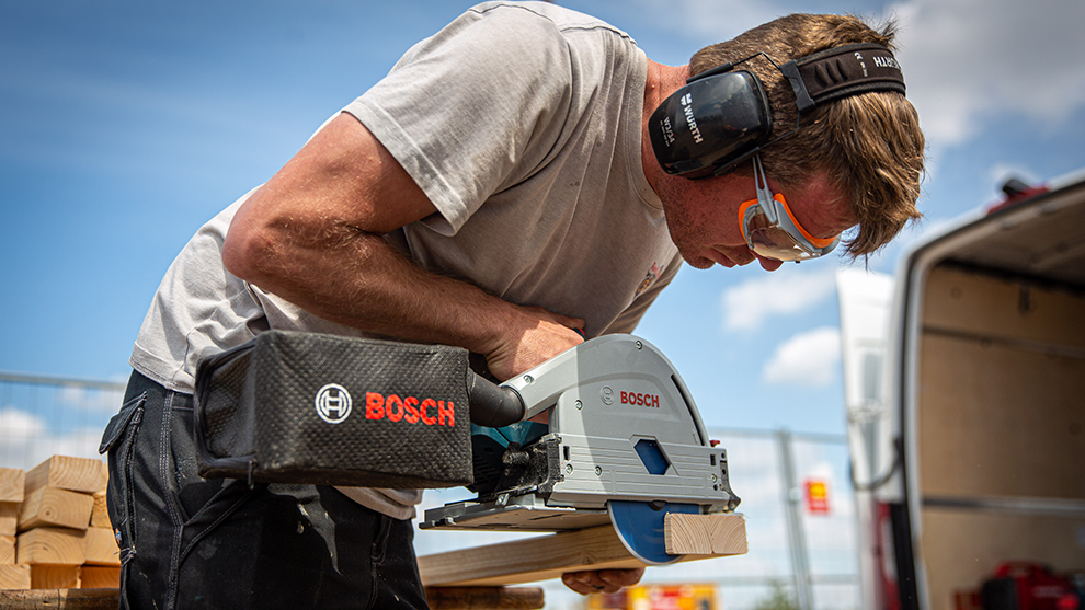 Mitre Saw A craftsman is cutting wood with a blue Bosch Professional saw.