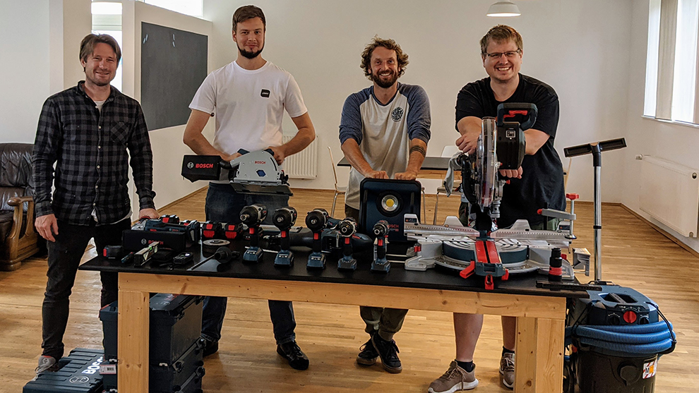 Team Four men are standing at a table with Bosch tools in a bright room.