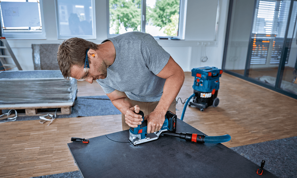 A man is using a Bosch Professional plunge saw in a modern room.