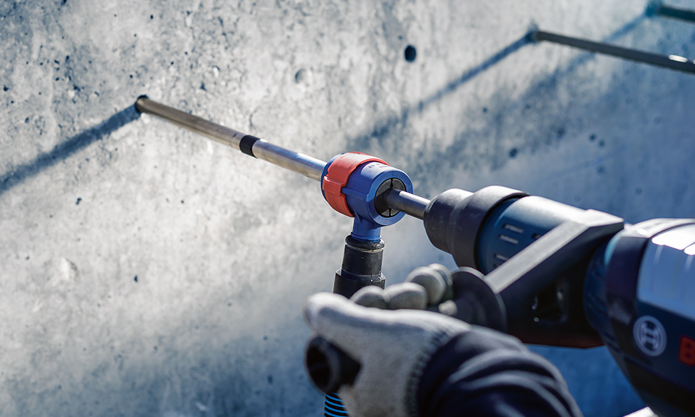A Bosch Professional tool is drilling into a gray concrete wall.
