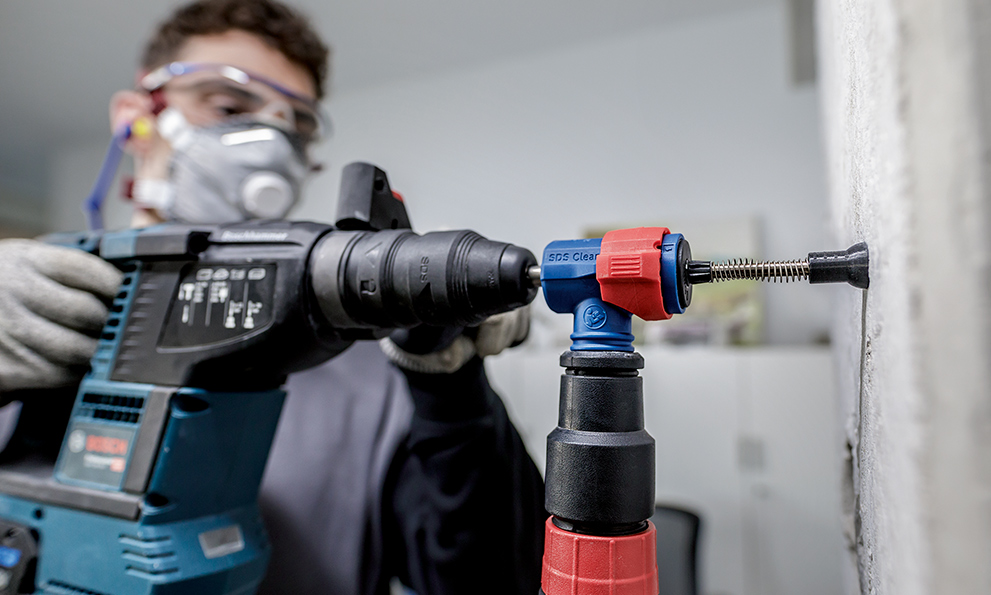 A Bosch Professional hammer drill is being inserted into a wall.