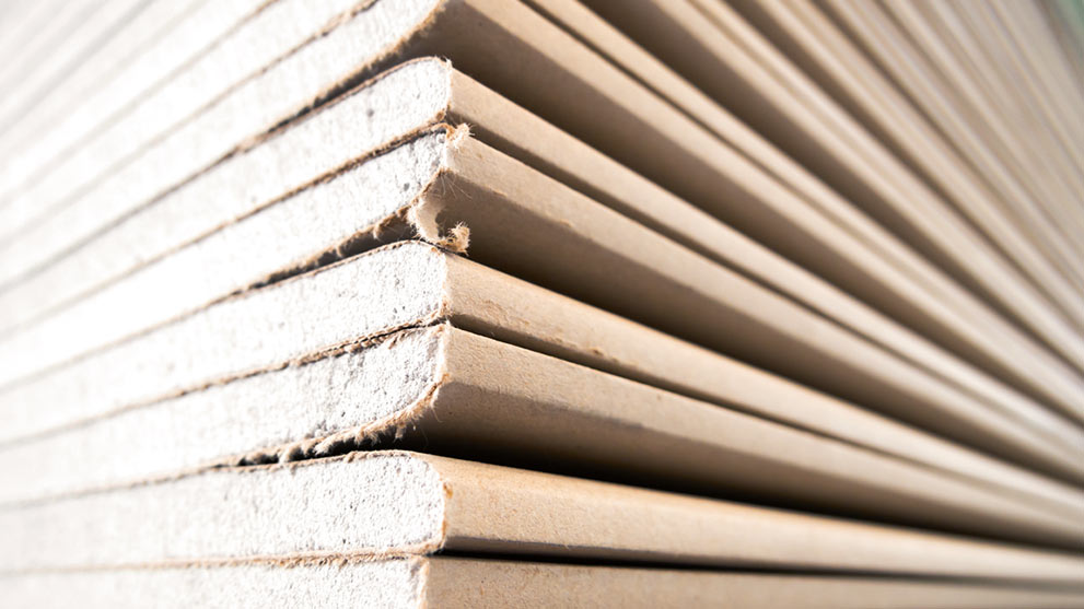 Stacked gray panels made of wood-based material in narrow layers.