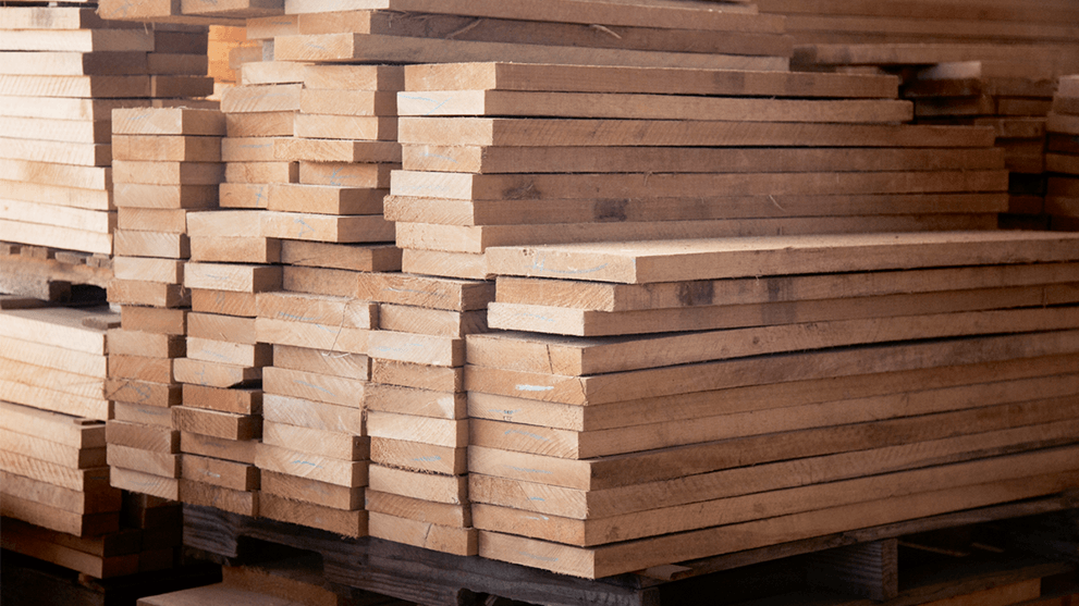 Stack of light wooden boards on a pallet in a warehouse.