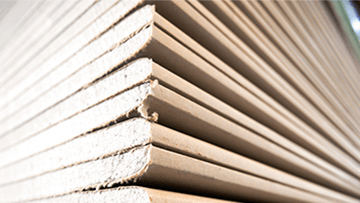 Stacked, light brown panels made of wood-based material with smooth edges.