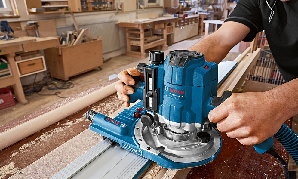 PLANING WOOD WITH PLANERS A blue Bosch Professional router is held over wood.