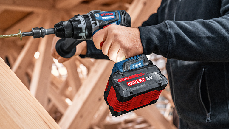 Bosch Professional cordless screwdriver with red 18V battery in wood texture.