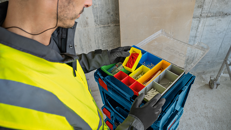 An open blue Bosch Professional tool case with various screwdrivers, a tape measure, and a level, on a light background.