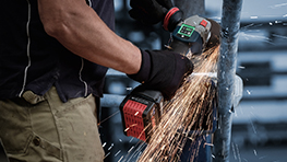 A craftsman is cutting metal with a Bosch tool, sparks are flying.