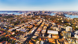 Aerial view of a city with buildings, trees, and water in the background.