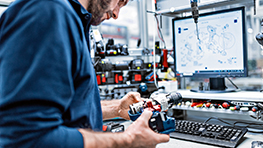 A man in blue clothing checks a Bosch Professional tool on the table.