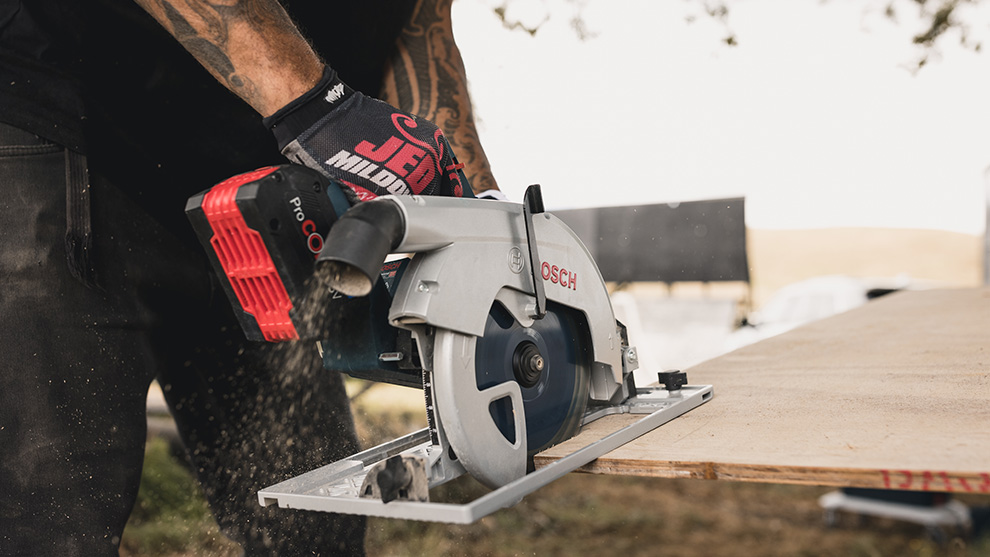 A Bosch Professional circular saw is cutting wood on a workbench.